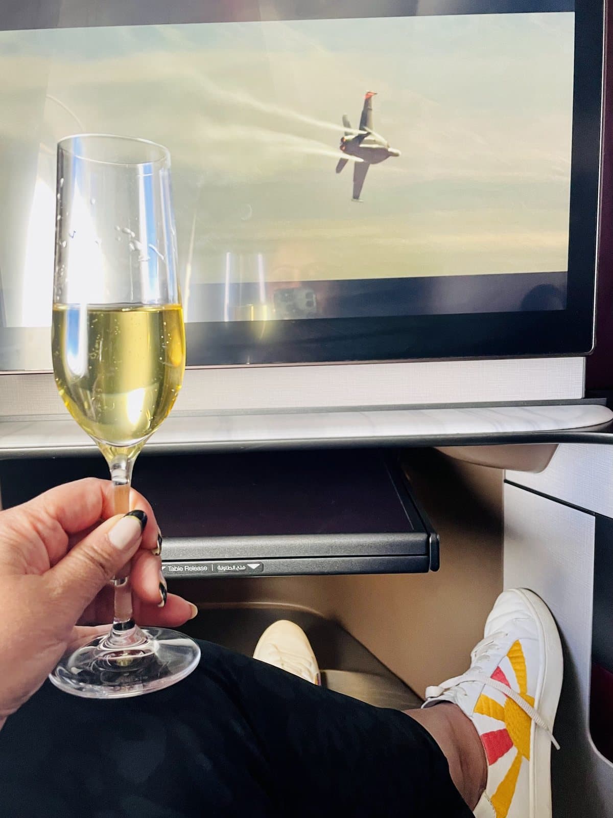 A glass of champagne held up in a Qatar Airways business class suite.